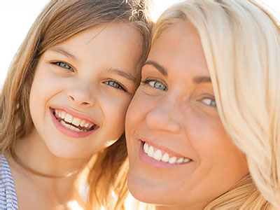 Happy mother and child girl outdoors, Kary Dental